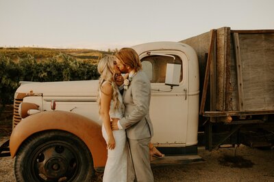 bride and groom kissing by old truck