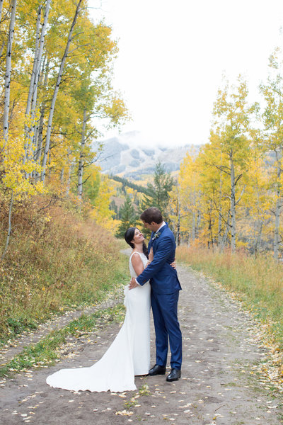 Bride and Groom standing in fall leaves at their Destination wedding in Beaver Creek