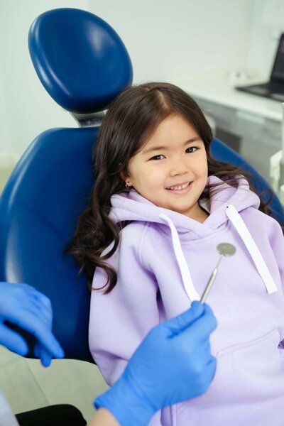 A child sits in a dentist chair smiling, representing Cassi Angier's casting in a commercial for a children's dentist.