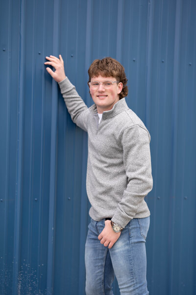 High school senior guy on blue wall
