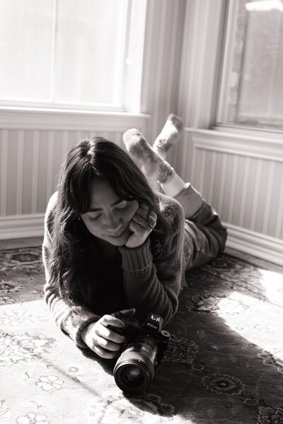 photographer brand photoshoot laying on the ground holding her camera