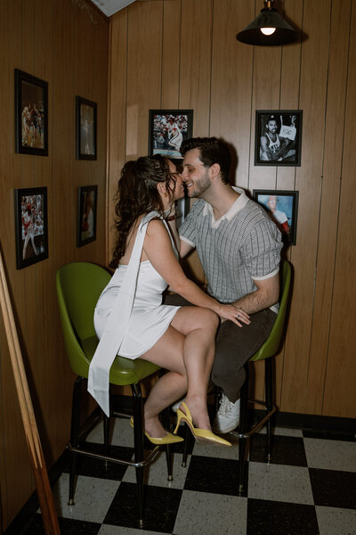 man and woman sitting in green chairs while kissing