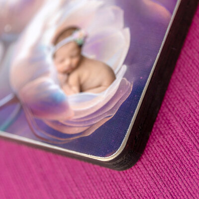 Framed print of a newborn girl in a purple frame with a white mat