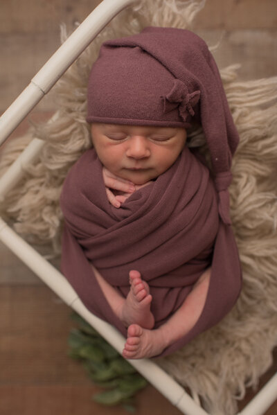 Baby girl wrapped in mauve wrap with hat, matching bow