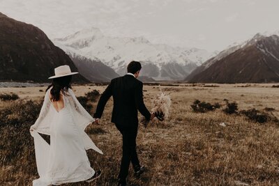Mt Cook wedding New Zealand - couple running along the road with snow top mountains in the back ground