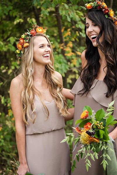 Bridesmaids laughing together while wearing fall flower crowns