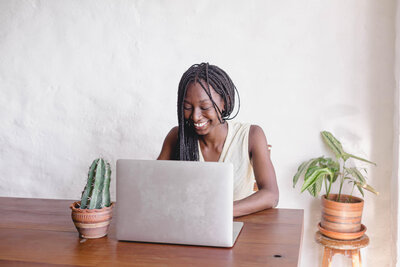 A woman on a laptop smiling.