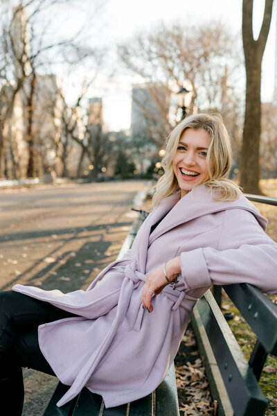 woman sitting on a bench with her arm over the top while smiling