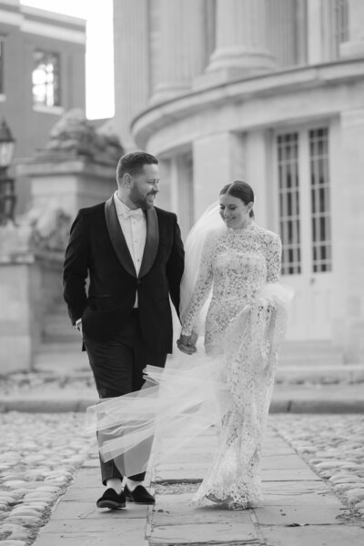 Editorial wedding portrait of bride and groom at Philadelphia’s Merchants Exchange Building, featuring a long sleeve lace Monique Lhuillier gown.