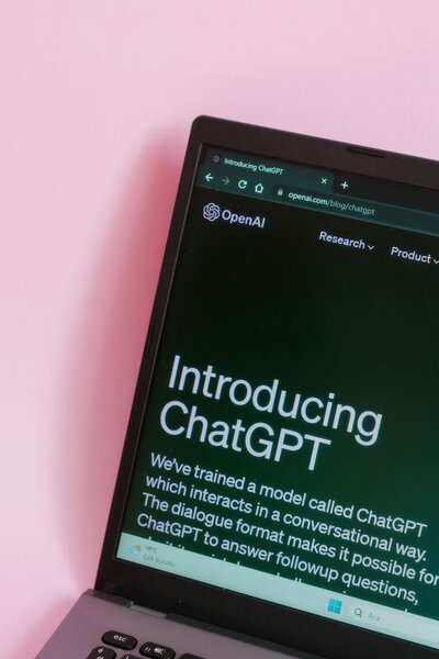 ChatGPT homescreen open on a laptop screen in front of a bright pink wall