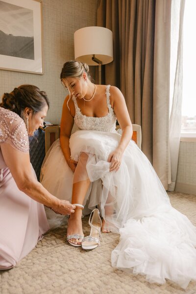 Bride and mother of bride putting on bridal heels.