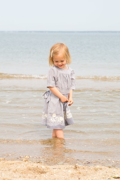 Little girl stands in water on Long Island Sound beach