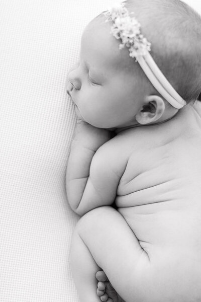 A black and white photo of a newborn baby sleeping during her in-studio photo session.