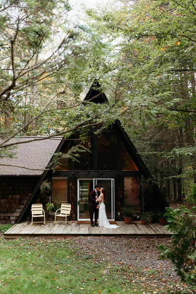 Bride and groom sharing an intimate moment outside a rustic cabin in the Poconos, Pennsylvania. A natural, unscripted elopement captured in a documentary wedding photography style.