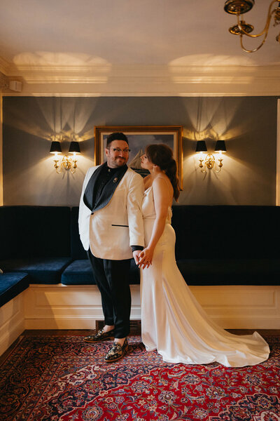 Bride and groom standing hand in hand in an intimate, warmly lit room