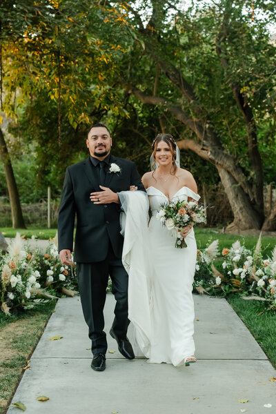 Bride and groom walking hand in hand through the scenic grounds of Hidden Hollow Weddings.