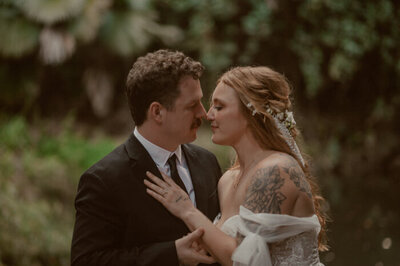bride smiling at the camera while groom nuzzles his face into hers