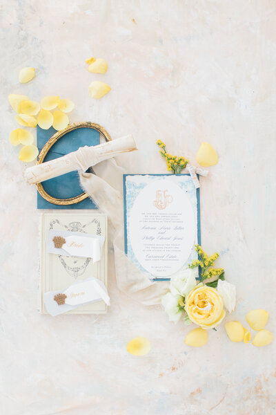 Flat lay photo of a blue and white wedding stationery suite and yellow flowers