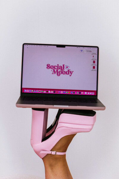 Social Moody Logo on laptop screen being balanced on pink heels