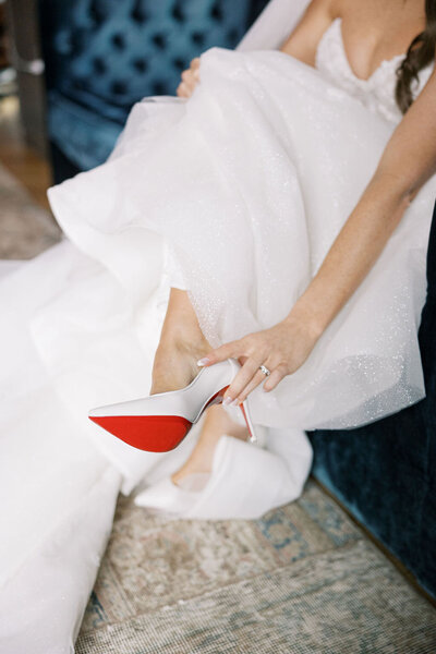 Bride slipping on red-soled designer wedding heels during wedding prep, a stylish moment from an Austin wedding planner’s curated day.