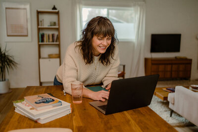 Woman working on laptop and smiling.