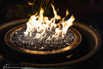 Bright flames burning on crystal fire stones surrounded by water spilling into an Aquascape bowl