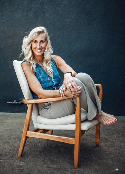 PDX realtor Stephanie sits in a chair and smiles at the camera.