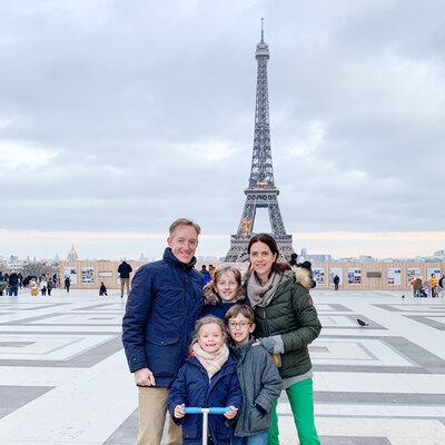 Family parents and three kids standing in front of the Eiffel tower in Paris in winter