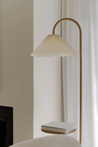 A brass floor lamp with cream shade