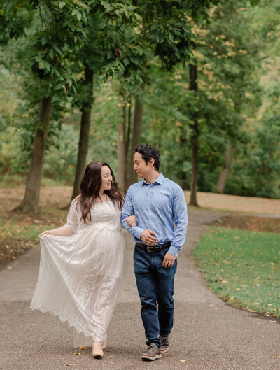 husband pregnant mother in white lace dress walking together for maternity portraits at squires castle