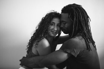 A Hispanic woman and black man hold each other while sitting on the floor