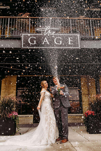 Bride and Groom in front of The Gage in Milwaukee spraying Champagne by wedding planners in wisconsin.