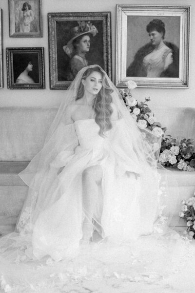 Black and white photo of bride on a couch with veil over 