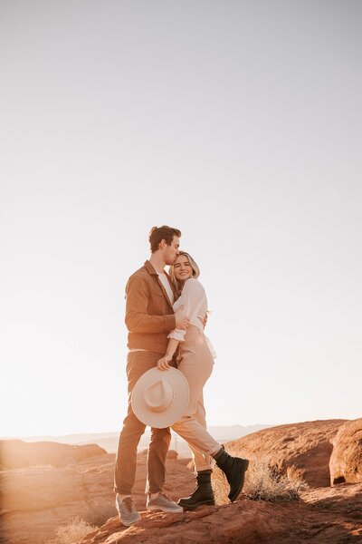 engaged couple standing on the red rocks in st. george, utah taken by jackson hole wedding photographer adrian wayment photo