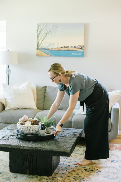 Kim Kussman, Utah Realtor & Owner of Nurture Lane, arranging a centerpiece on a coffee table of a realty listing