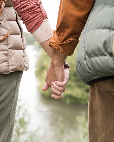 close-up-couple-holding-hands-near-river
