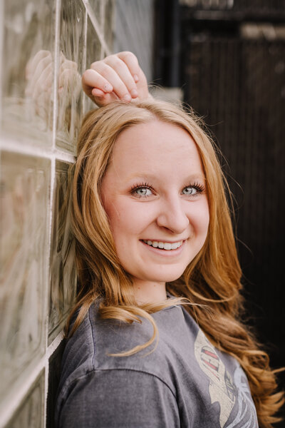 A young women posed next to a glass wall.