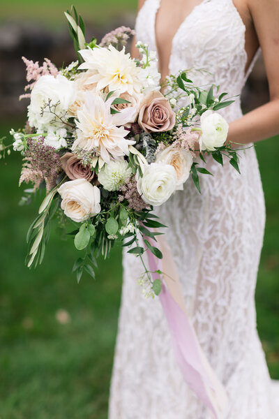 Bride holding a green and white bridal bouquet outdoors