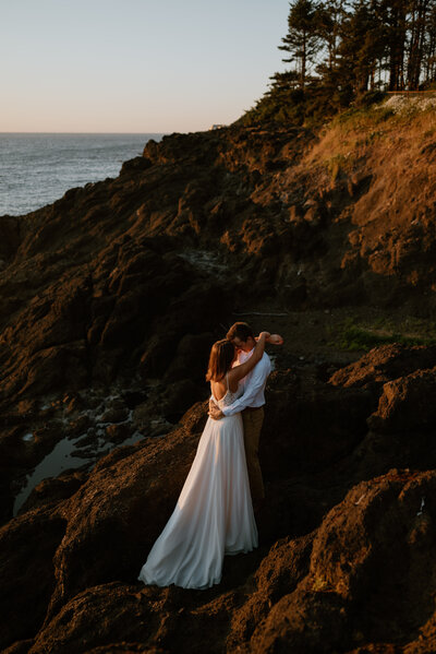 A couple holds eachother during their elopement on the rocky  coast of Oregon.
