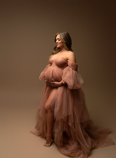 Soft blush-toned tulle maternity robe in warm lighting, perfect for showcasing red, pink, and purple dress options in the studio