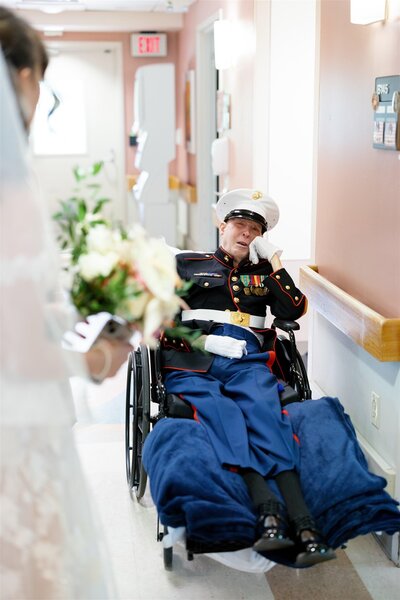 An older grandparent in a wheelchair smiling at their grandchild on their wedding day 