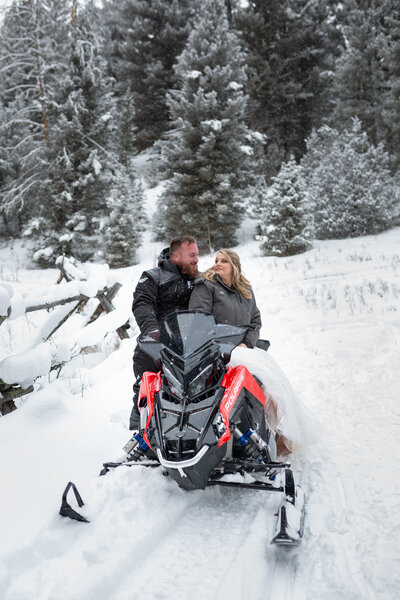 A couple sit on top of a snowmobile during their winter elopement in Montana.