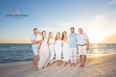 Beautiful family of eight wearing white and blue on Bradenton Beach at sunset