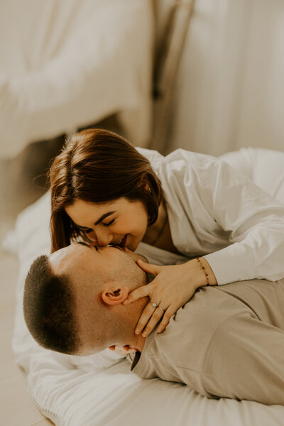 Femme enceinte, en sous-vêtements, assise dans grand fauteuil rond en bois avec coussin dans un décor cosy, à mon studio photo en Vendée.