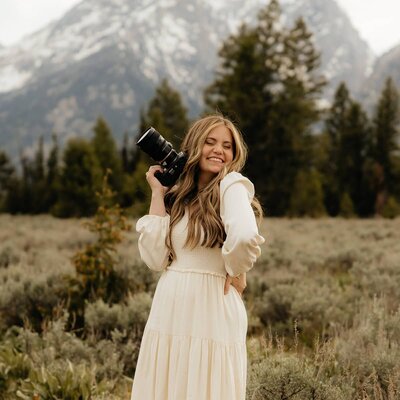 Salt Lake City photographer smiling and holding a camera near her face