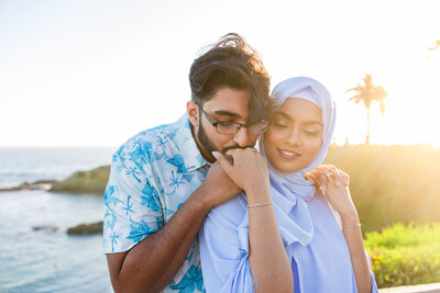 groom kisses the hand of his bride-to-be on the beach