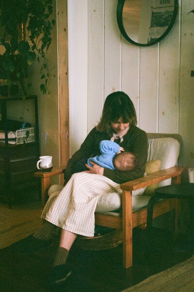 film photo of a woman breastfeeding a baby in a wool sweater