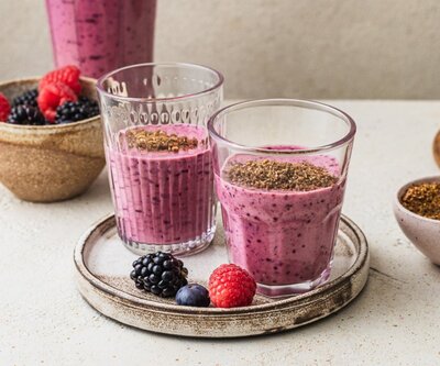 Purple berry glow smoothie topped with flaxseeds – a hormone-supportive breakfast rich in antioxidants and protein