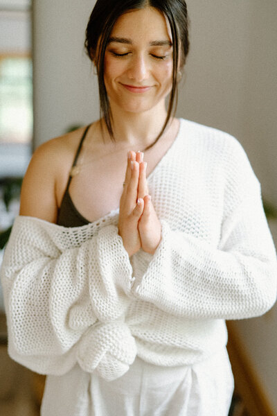 Woman holding her hands together against her chest at Alyn Wellness Studio