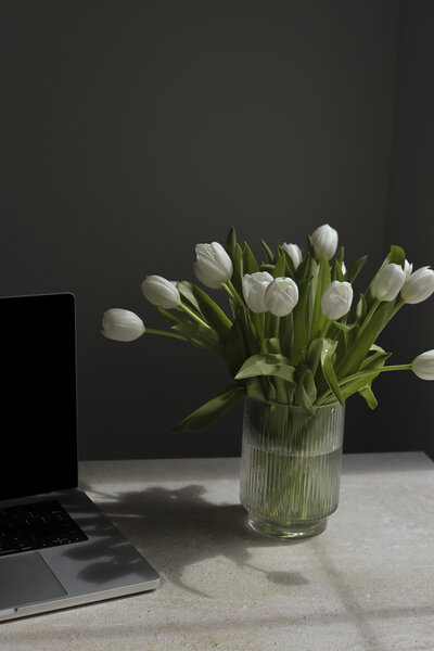 flowers sitting on a desk next to an open laptop